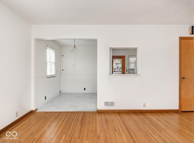 unfurnished room with hardwood / wood-style floors and a textured ceiling