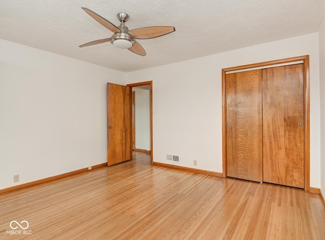 unfurnished bedroom with a textured ceiling, light hardwood / wood-style floors, a closet, and ceiling fan