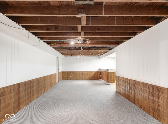 basement with carpet and wood walls