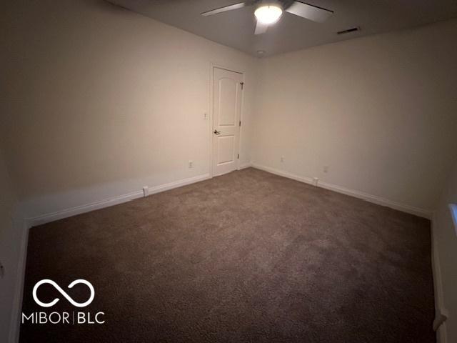 empty room with ceiling fan and dark carpet