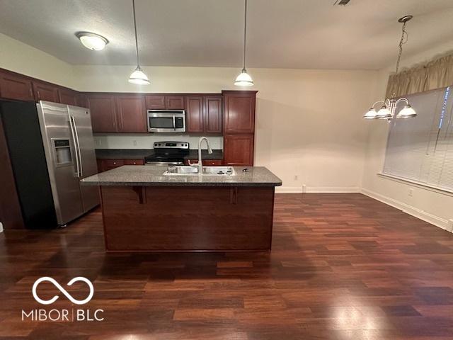 kitchen with sink, dark hardwood / wood-style floors, pendant lighting, a kitchen island with sink, and appliances with stainless steel finishes