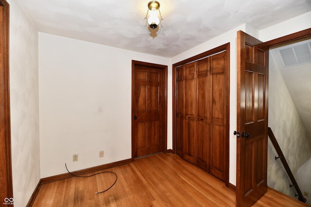 unfurnished bedroom with light hardwood / wood-style floors and a closet