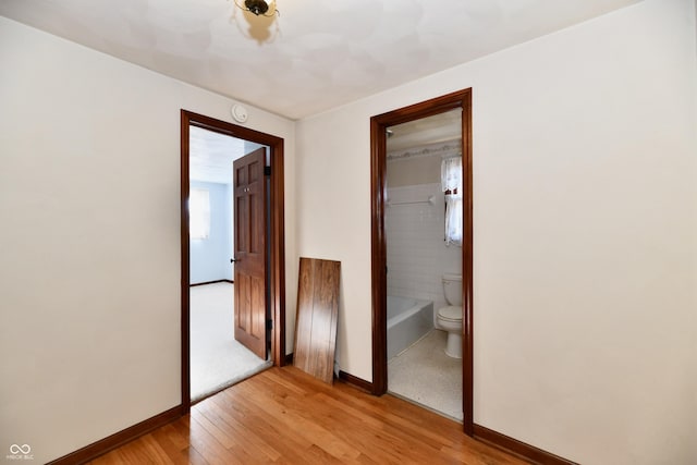 unfurnished bedroom featuring connected bathroom, light hardwood / wood-style floors, and a closet