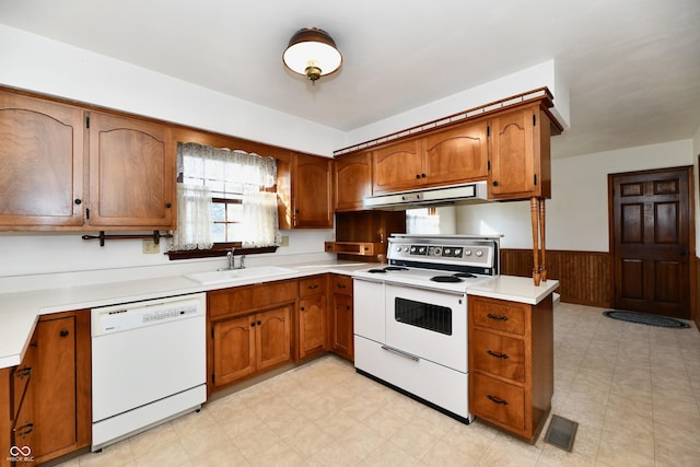 kitchen with wooden walls, sink, and white appliances