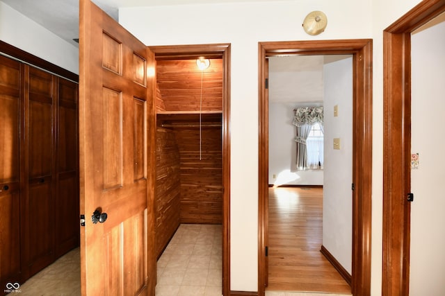 hallway with light hardwood / wood-style floors and wood walls