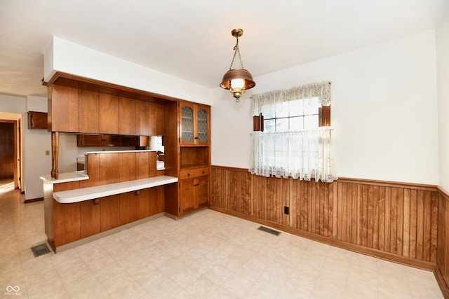 kitchen with kitchen peninsula, wooden walls, and pendant lighting