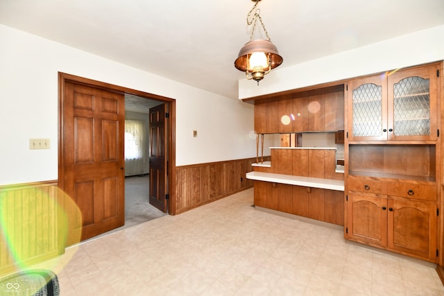 kitchen featuring kitchen peninsula, wooden walls, and decorative light fixtures