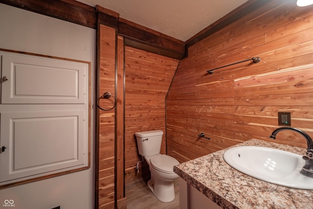 bathroom with hardwood / wood-style floors, vanity, toilet, and wood walls