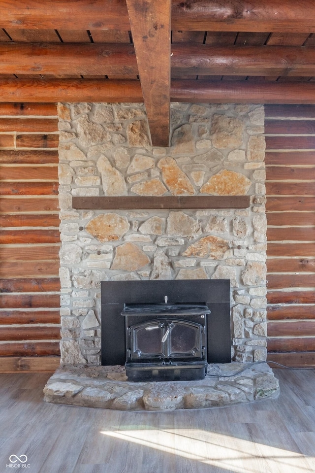 details with hardwood / wood-style floors, a wood stove, beamed ceiling, and log walls