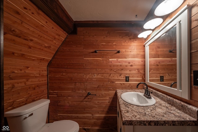 bathroom featuring vanity, wood walls, and toilet