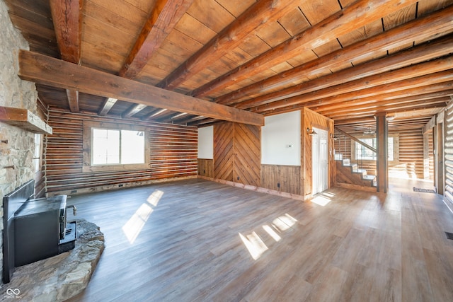 unfurnished living room with a wood stove, wooden ceiling, beamed ceiling, wooden walls, and hardwood / wood-style flooring