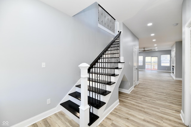 stairs featuring wood-type flooring and ceiling fan