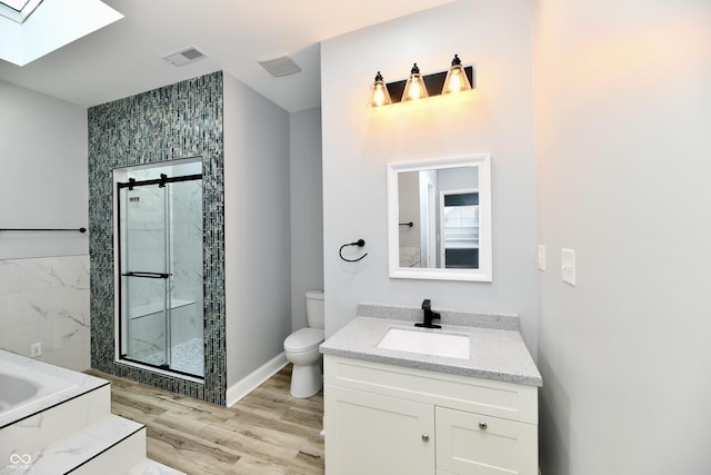 full bathroom with a skylight, vanity, independent shower and bath, hardwood / wood-style floors, and toilet