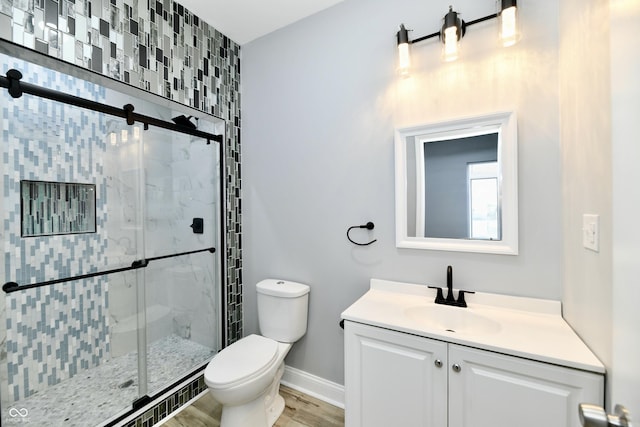 bathroom featuring toilet, vanity, a shower with shower door, and hardwood / wood-style flooring