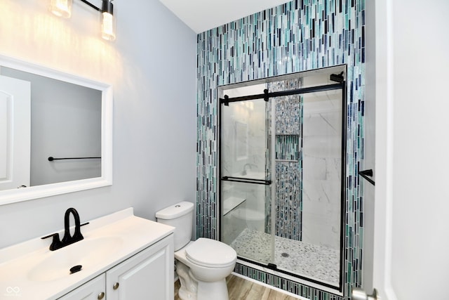 bathroom with vanity, toilet, an enclosed shower, and wood-type flooring