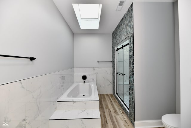 bathroom featuring a skylight, toilet, plus walk in shower, and hardwood / wood-style flooring