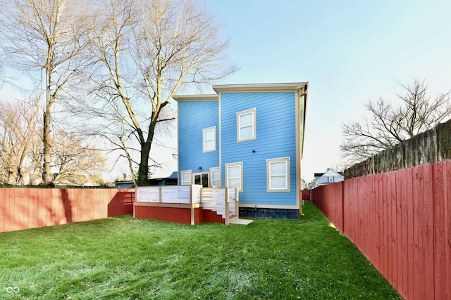 rear view of property featuring a yard and a wooden deck