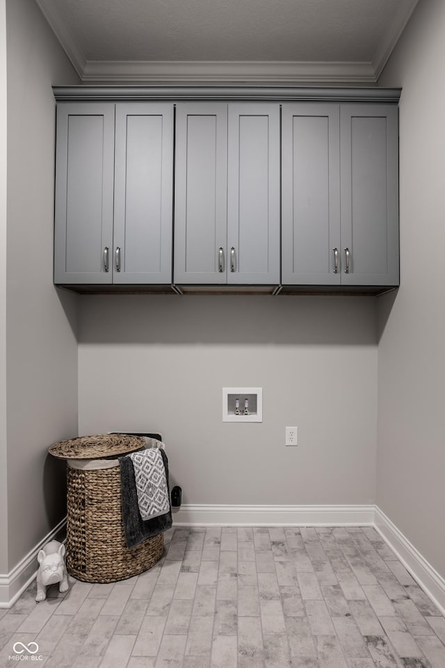 clothes washing area with cabinets, washer hookup, and crown molding