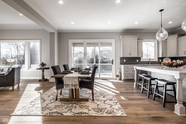 dining area with ornamental molding, sink, and light hardwood / wood-style flooring