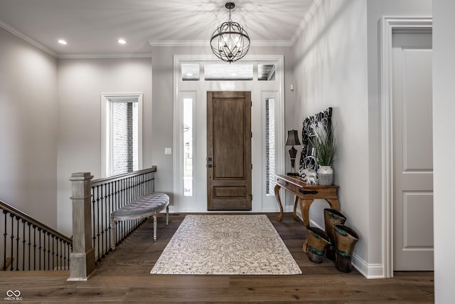 entrance foyer with dark hardwood / wood-style floors, crown molding, and a notable chandelier