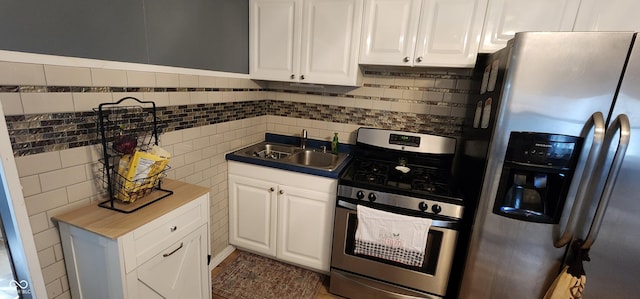 kitchen featuring sink, tasteful backsplash, tile walls, appliances with stainless steel finishes, and white cabinets