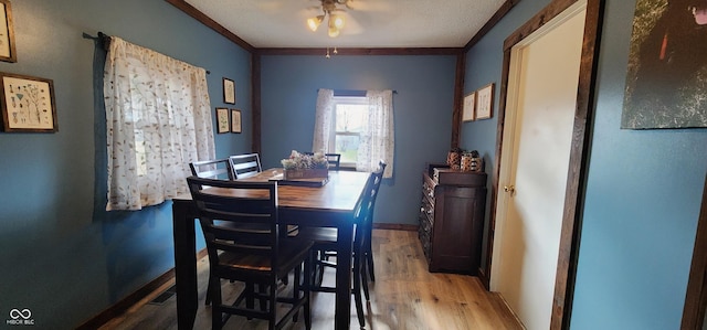 dining area featuring crown molding, wood-type flooring, ceiling fan, and a textured ceiling