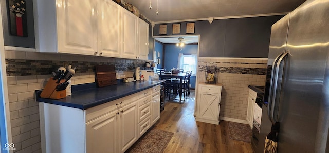 kitchen with stainless steel fridge, white cabinetry, tile walls, wood-type flooring, and ornamental molding