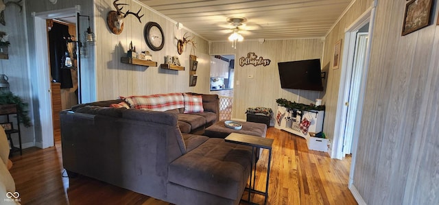 living room featuring hardwood / wood-style flooring, ceiling fan, and wooden walls