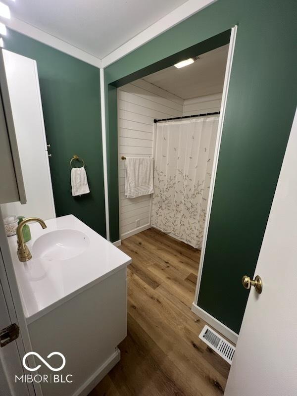 bathroom featuring vanity, hardwood / wood-style flooring, and ornamental molding