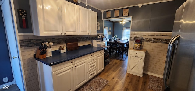 kitchen with white cabinetry, tile walls, stainless steel fridge, ceiling fan, and hardwood / wood-style floors