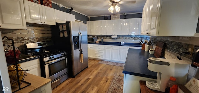 kitchen with ornamental molding, appliances with stainless steel finishes, white cabinets, and light hardwood / wood-style floors