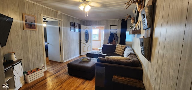 living room with wood-type flooring, ceiling fan, and wood walls