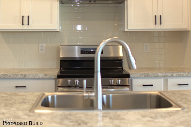 kitchen featuring light stone counters, white cabinetry, range hood, and tasteful backsplash