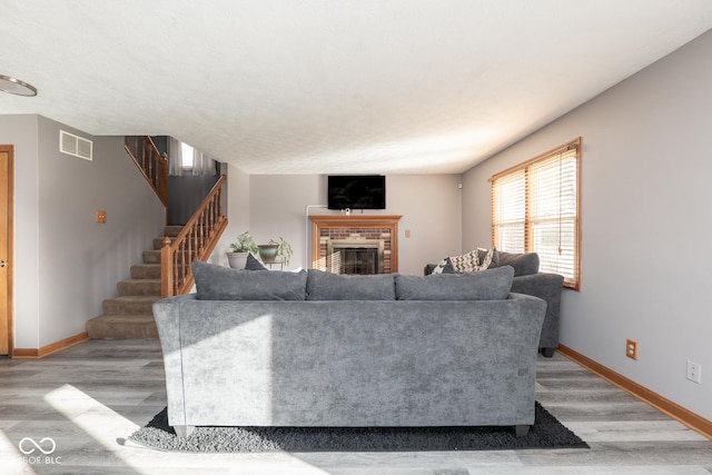 living room with light wood-type flooring and a brick fireplace