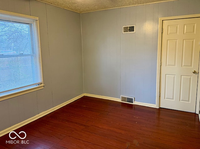 unfurnished room with a textured ceiling, dark hardwood / wood-style flooring, and wooden walls