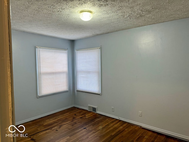 empty room with a textured ceiling and dark hardwood / wood-style floors