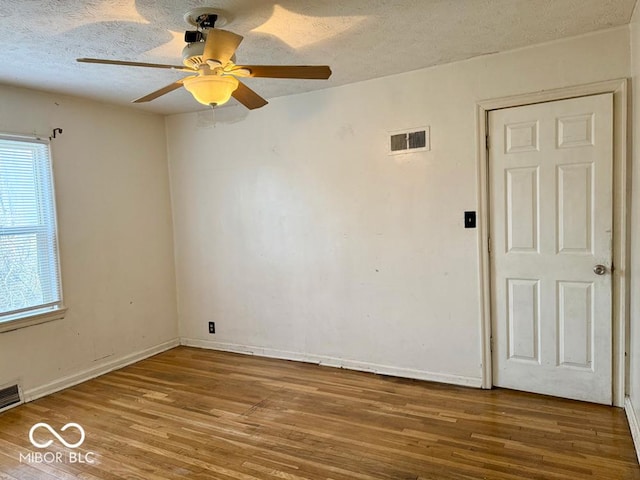 empty room featuring hardwood / wood-style flooring, ceiling fan, and a textured ceiling