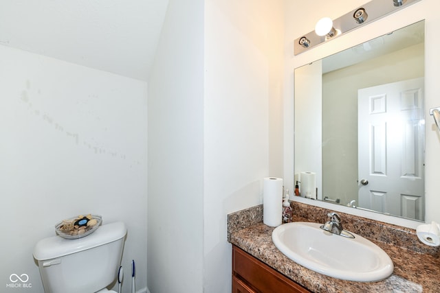 bathroom with vanity, toilet, and lofted ceiling