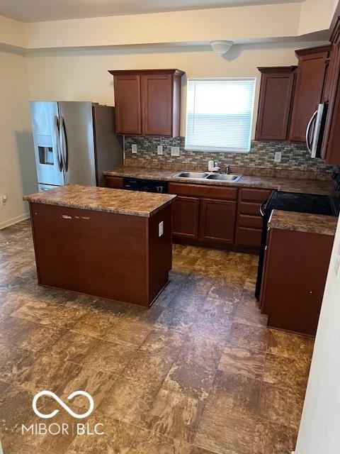 kitchen with appliances with stainless steel finishes, a center island, decorative backsplash, sink, and light stone counters