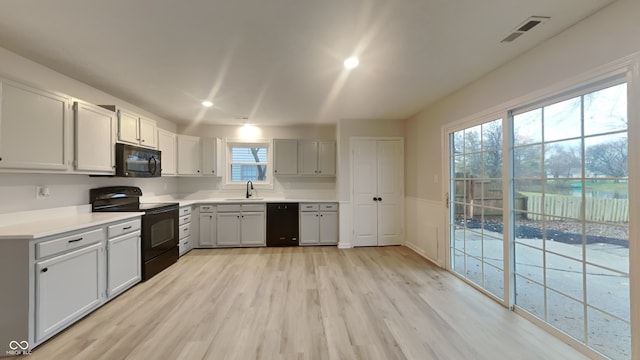 kitchen featuring sink, light hardwood / wood-style floors, and black appliances