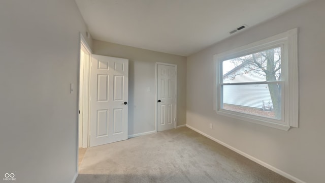 unfurnished bedroom with light colored carpet and a closet