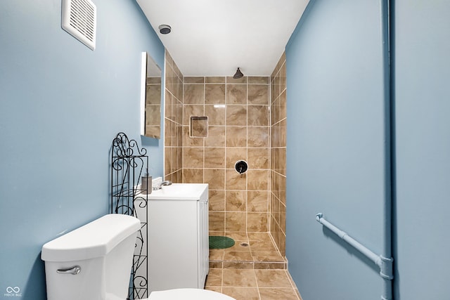 bathroom featuring tiled shower, tile patterned floors, vanity, and toilet