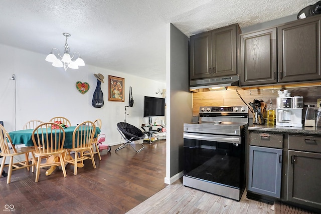 kitchen with light wood-type flooring, backsplash, a textured ceiling, a notable chandelier, and stainless steel electric range