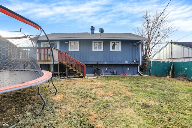 rear view of house with a lawn and a trampoline