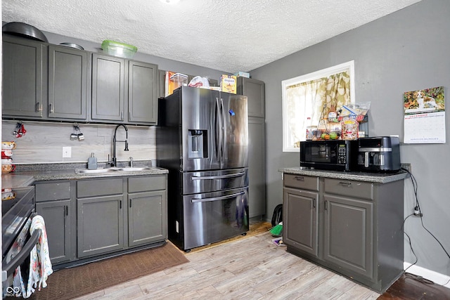 kitchen with sink, electric range oven, stainless steel fridge, gray cabinets, and light wood-type flooring