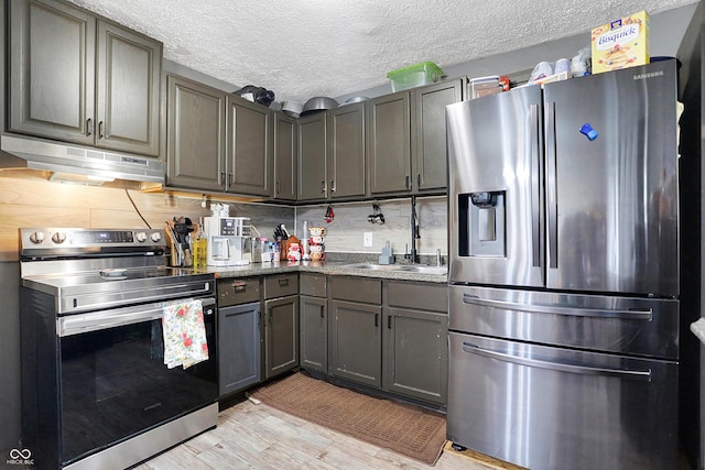 kitchen featuring gray cabinets, light wood-type flooring, a textured ceiling, and appliances with stainless steel finishes