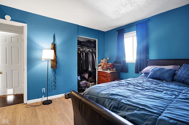 bedroom with a closet, hardwood / wood-style floors, and a textured ceiling