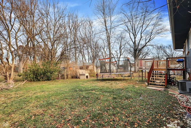 view of yard featuring a trampoline, a deck, and cooling unit