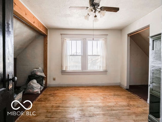 unfurnished dining area with lofted ceiling, ceiling fan, light wood-type flooring, and a textured ceiling