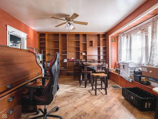 home office with light hardwood / wood-style flooring and ceiling fan